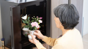 仏壇に花を供える高齢者の女性